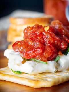 Portrait close up image of a tomato and chilli jam being served with cheese and crackers