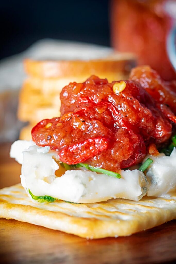 Portrait close up image of a tomato and chilli jam being served with cheese and crackers