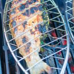 Portrait image of a whole trout that has been cooked on a BBQ in a fish basket