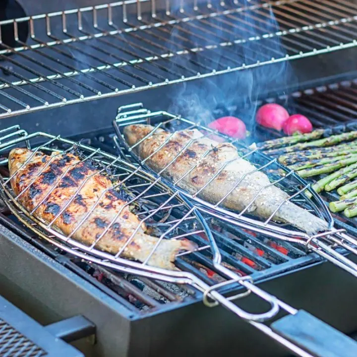 Square image of 2 whole trout that has been cooked on a BBQ in fish baskets