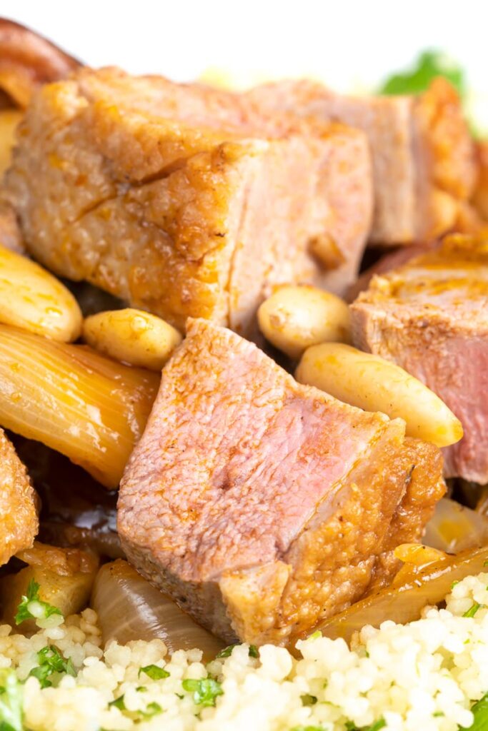 Portrait close up image of a light duck breast stew with North African flavours served with buttered couscous