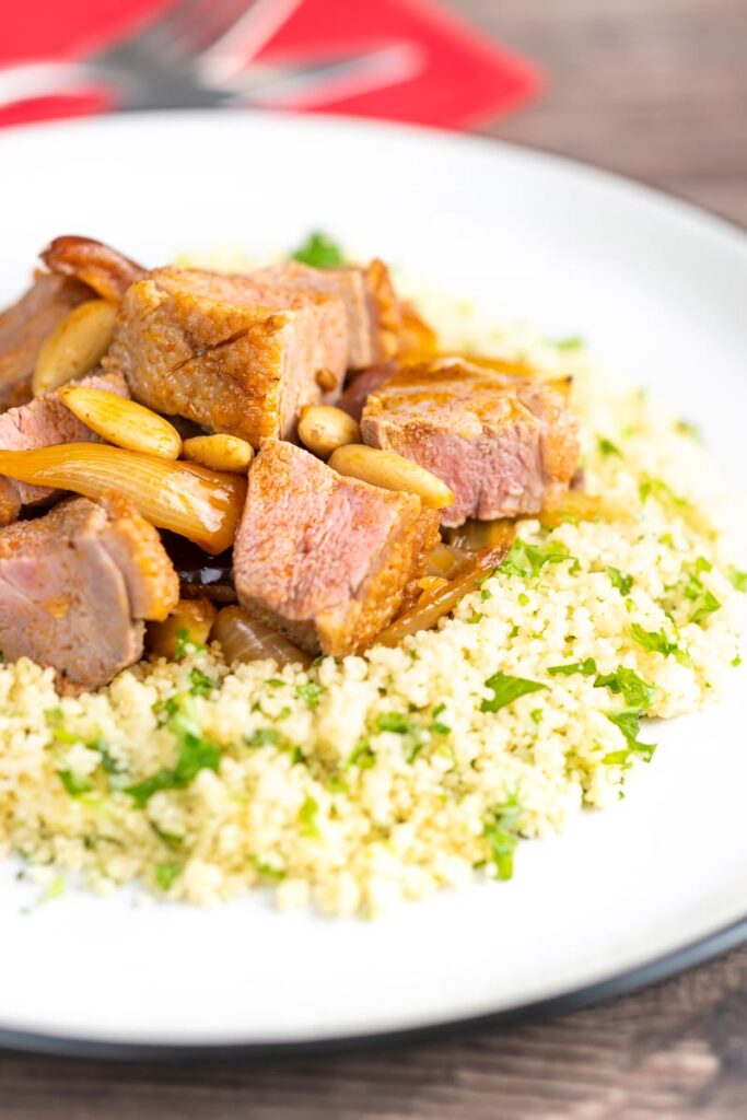 Portrait image of a light duck breast tagine with North African flavours served with buttered couscous
