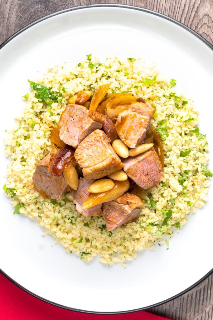 Portrait overhead image of a light duck breast stew with North African flavours served with buttered couscous
