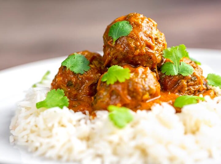 Landscape image of spicy venison meatballs served with basmati rice and coriander leaved