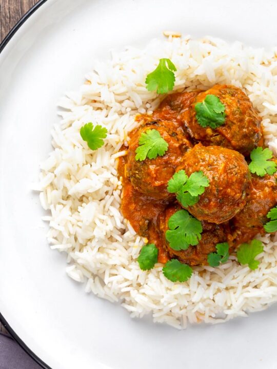 Portrait overhead image of spicy venison meatballs served with basmati rice and coriander leaves