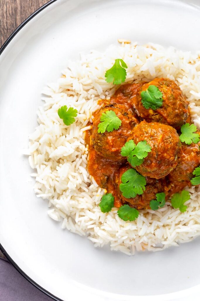 Portrait overhead image of spicy venison meatballs served with basmati rice and coriander leaves