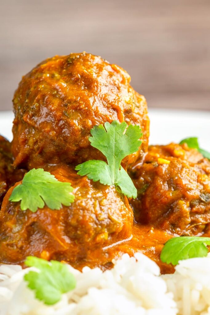Portrait close up image of spicy venison meatballs served with basmati rice and coriander leaves