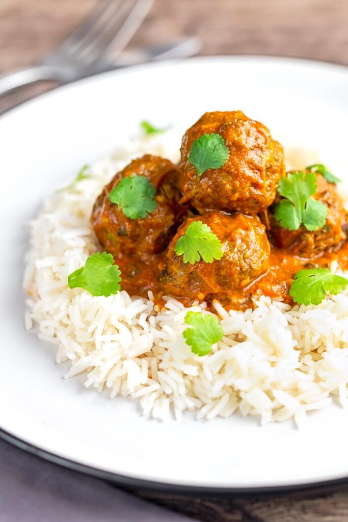Portrait image of spicy venison meatballs served with basmati rice and coriander leaves