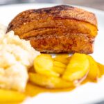 Portrait image of crispy Pork Belly served with apples and celeriac mash