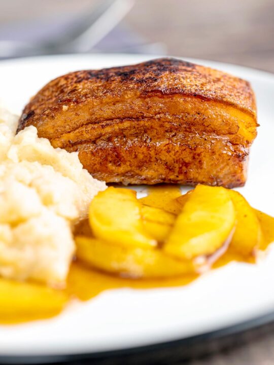 Portrait image of crispy Pork Belly served with apples and celeriac mash