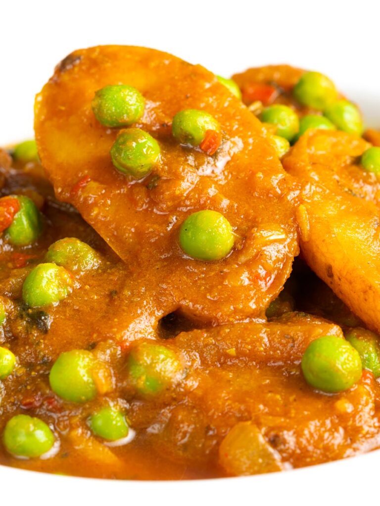 Portrait close up image of a pea and potato curry or aloo matar served in a white bowl