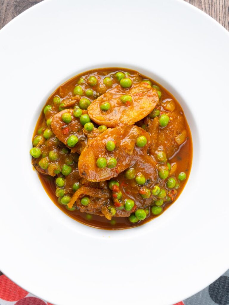Portrait image of a pea and potato curry or aloo matar served in a white bowl
