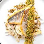 Portrait overhead image of pan fried sea bream fillet served with a parsley crumb and puy lentils with fennel