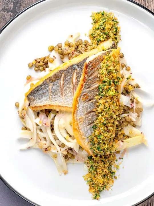 Portrait overhead image of pan fried sea bream fillet served with a parsley crumb and puy lentils with fennel