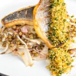 Portrait image of pan fried sea bream fillet served with a parsley crumb and puy lentils with fennel
