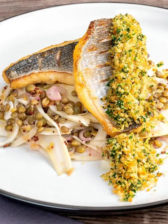 Portrait image of pan fried sea bream fillet served with a parsley crumb and puy lentils with fennel