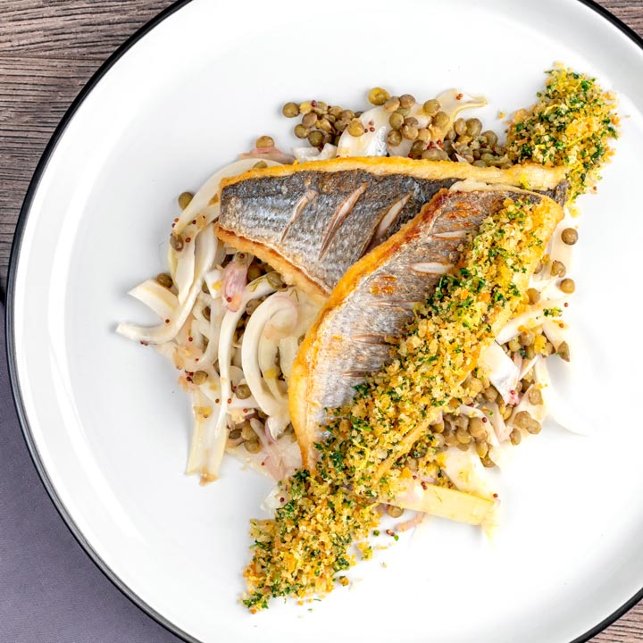 Square overhead image of pan fried sea bream fillet served with a parsley crumb and puy lentils with fennel