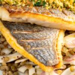Portrait close up image of pan fried sea bream fillet served with a parsley crumb and puy lentils with fennel
