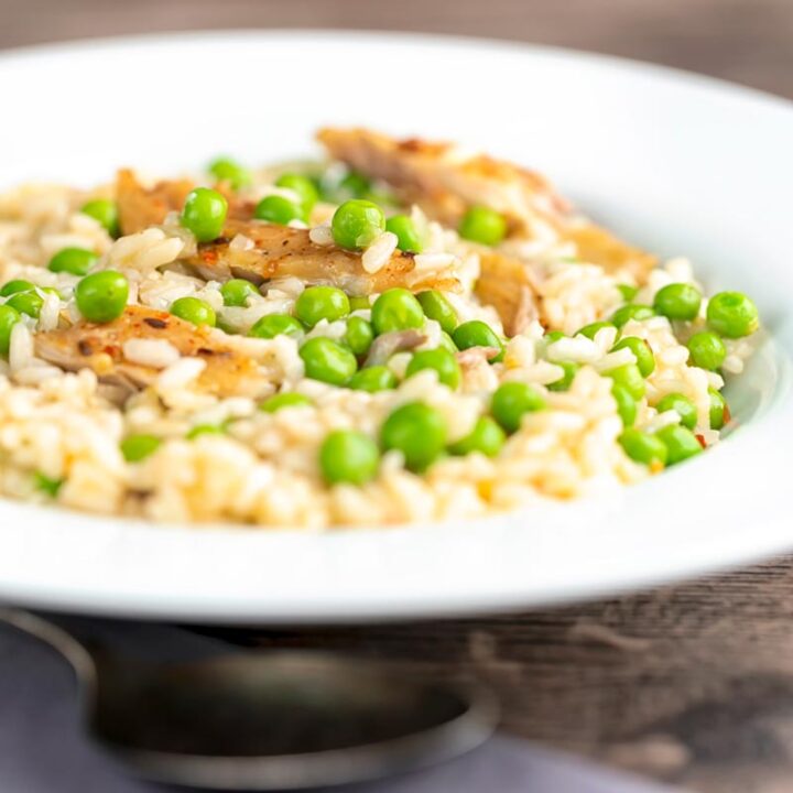 Square image of a smoked mackerel risotto with peas served in a shallow white bowl