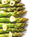 Portrait overhead image of buttery air fryer cooked asparagus with garlic slices