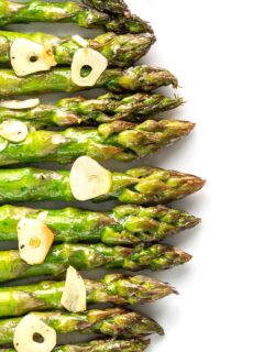 Portrait overhead image of buttery air fryer cooked asparagus with garlic slices