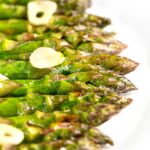 Portrait image of buttery air fryer cooked asparagus with garlic slices