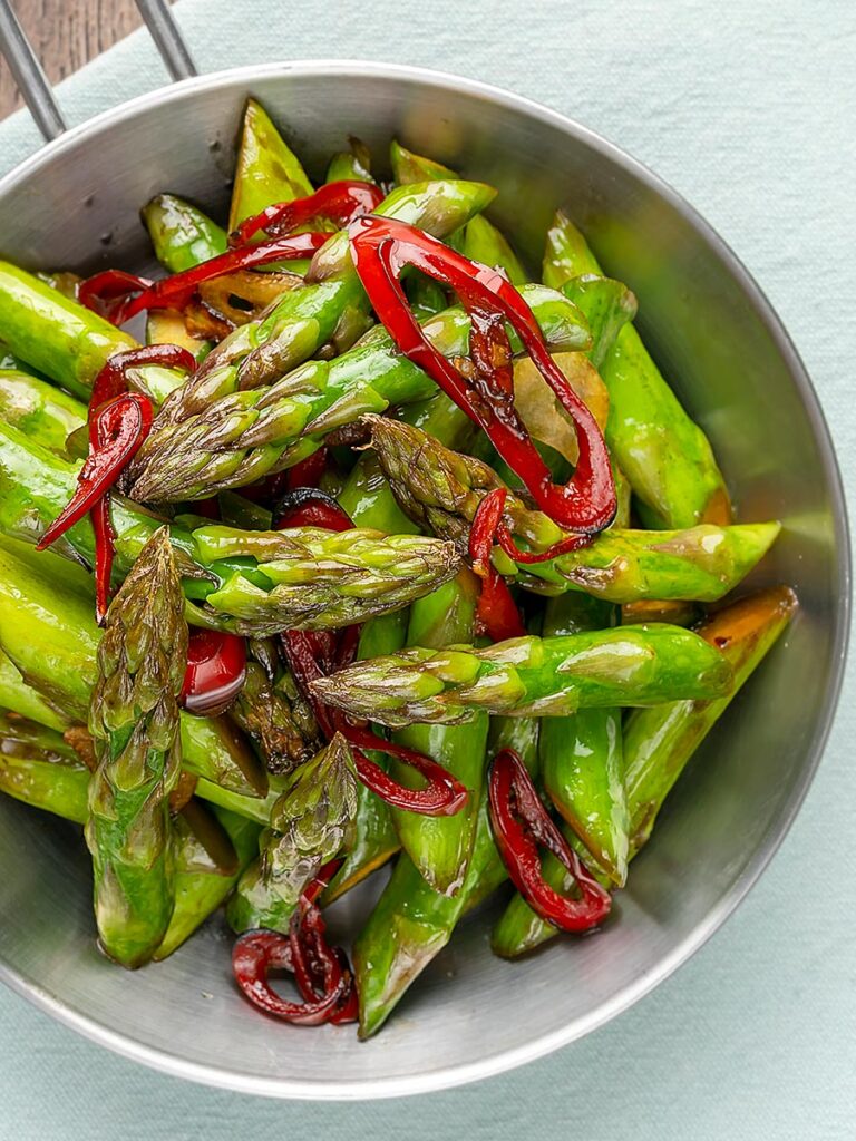 Portrait overhead image of asparagus stir fry with chilli and garlic served in a small frying pan