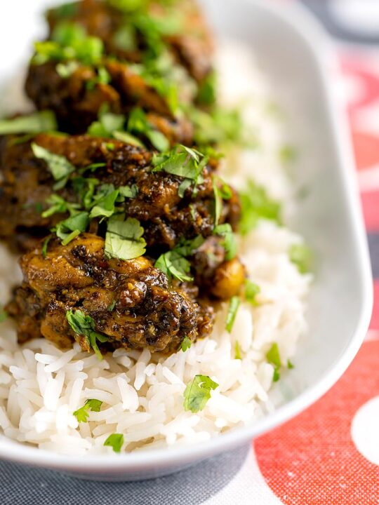 Portrait image of a dry pepper chicken Chettinad curry served on boiled basmati rice.