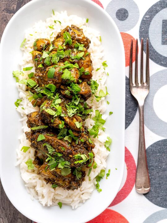 Portrait overhead image of a dry pepper chicken Chettinad curry served on boiled basmati rice.