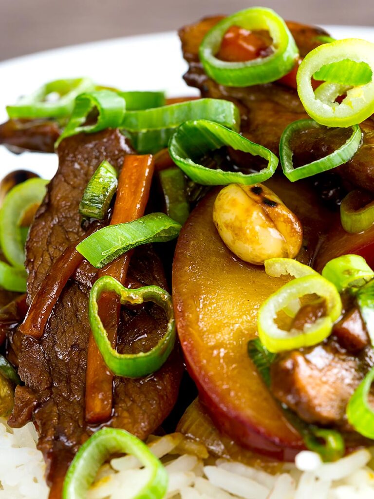 Portrait close up image of Chinese duck stir fry with plums served on white rice