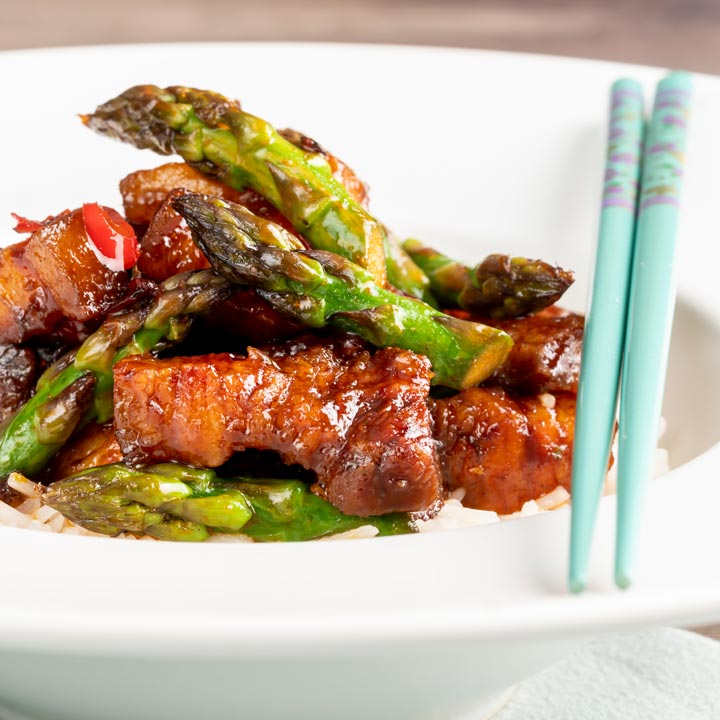 Square image of Korean Pork Belly cooked in a spicy coating with asparagus