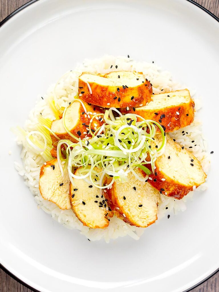Portrait overhead image of a gouchujang glazed Korean steamed chicken breast served with spring onions