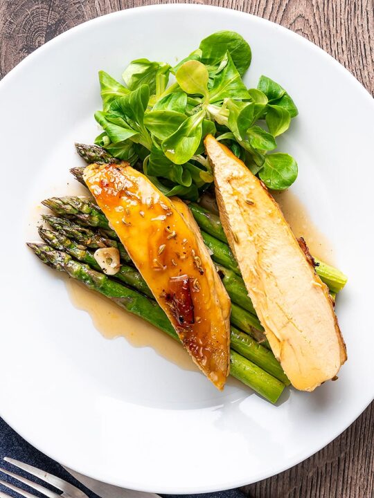 Portrait overhead image of a marmalade glazed chicken breast served with asparagus