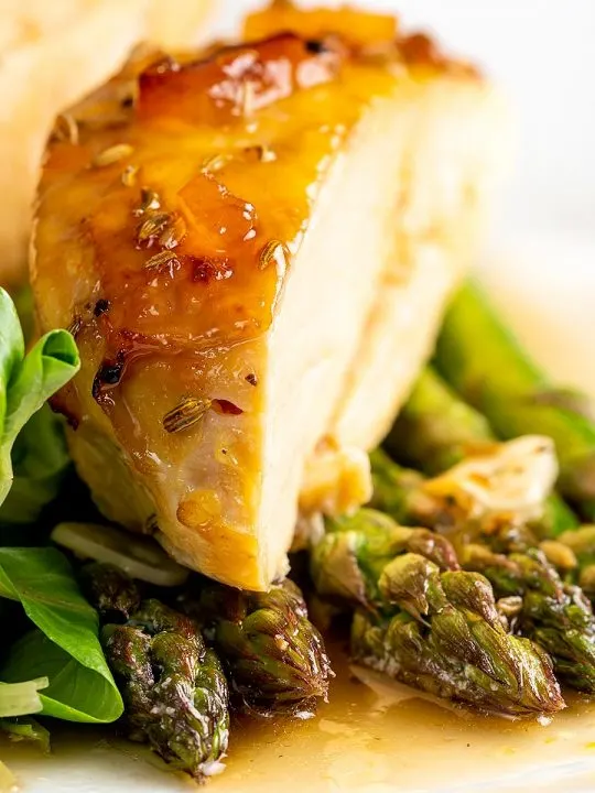 Portrait image marmalade chicken breast swerved with buttery asparagus