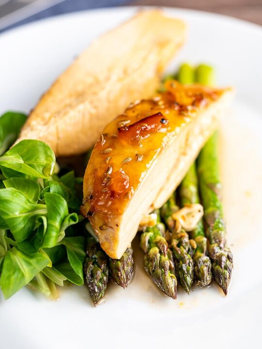Portrait image of a marmalade glazed chicken breast served with asparagus