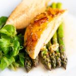 Portrait image of a marmalade glazed chicken breast served with asparagus with text overlay