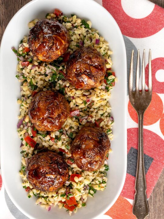 Portrait overhead image of North African influenced meatballs served on a tabbouleh salad in a white long bowl