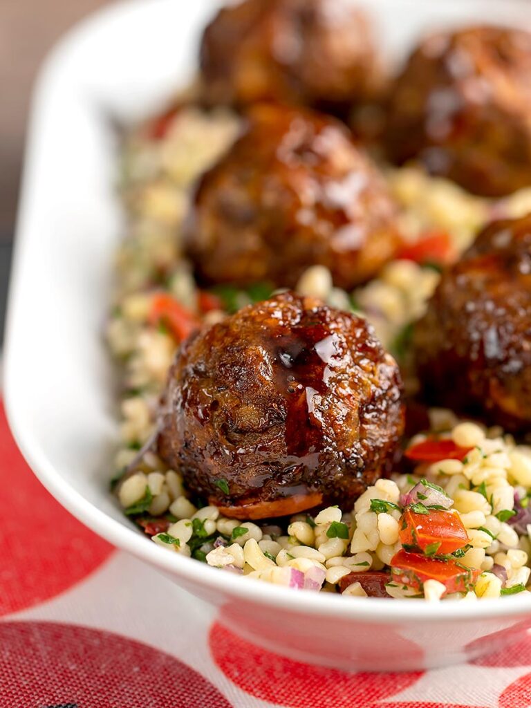 Portrait image of Moroccan influenced meatballs served on a tabbouleh salad in a white long bowl