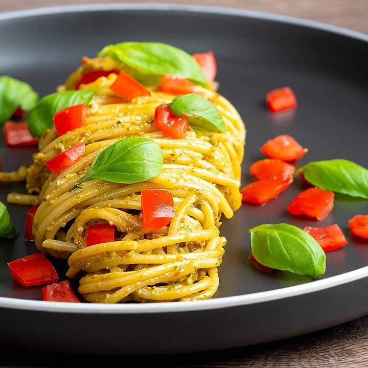 Square image of pesto alla trapanese served with spaghetti and tomato concasse and fresh basil