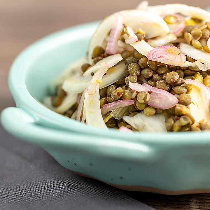 Square image of a pickled fennel salad with puy lentils served in a baby blue bowl
