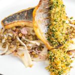 Portrait image of a pickled fennel salad with puy lentils served with sea bream fillets and a lemon and parsley crumb