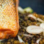 Portrait image of a pickled fennel salad with puy lentils served with pan seared salmon fillet