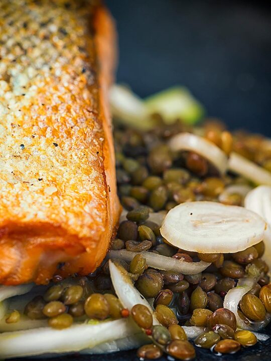 Portrait image of a pickled fennel salad with puy lentils served with pan seared salmon fillet