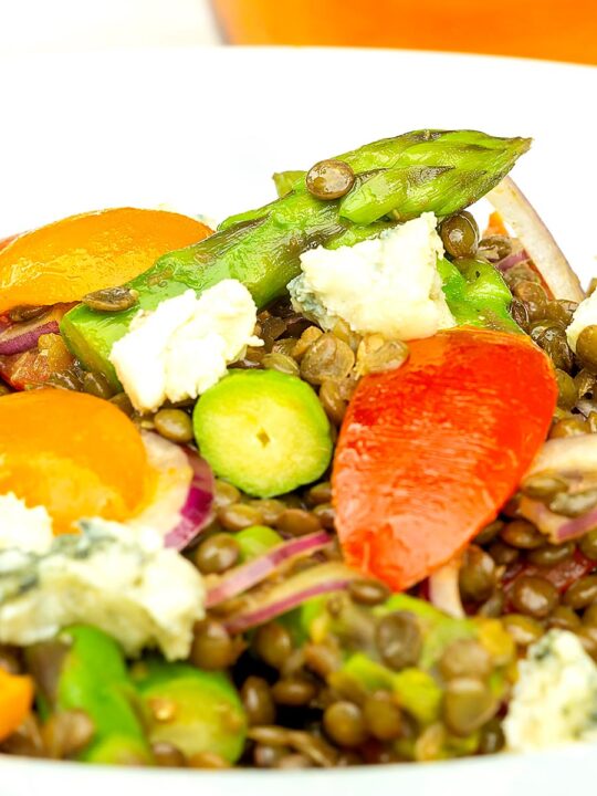 Portrait close up image of an asparagus salad with lentils, blue cheese and tomatoes