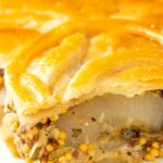 Portrait close up image of a slice of cheese and onion pie with wholegrain mustard