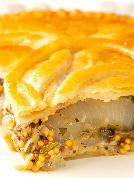Portrait close up image of a slice of cheese and onion pie with wholegrain mustard