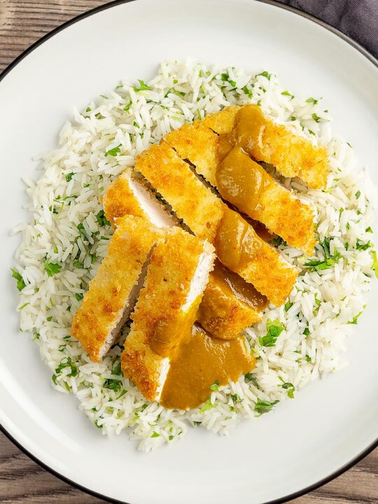Portrait overhead image of a chicken katsu curry with sliced crispy chicken breast served with coriander rice