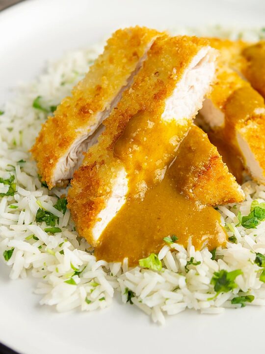 Portrait image of a chicken katsu curry with sliced crispy chicken breast served with coriander rice