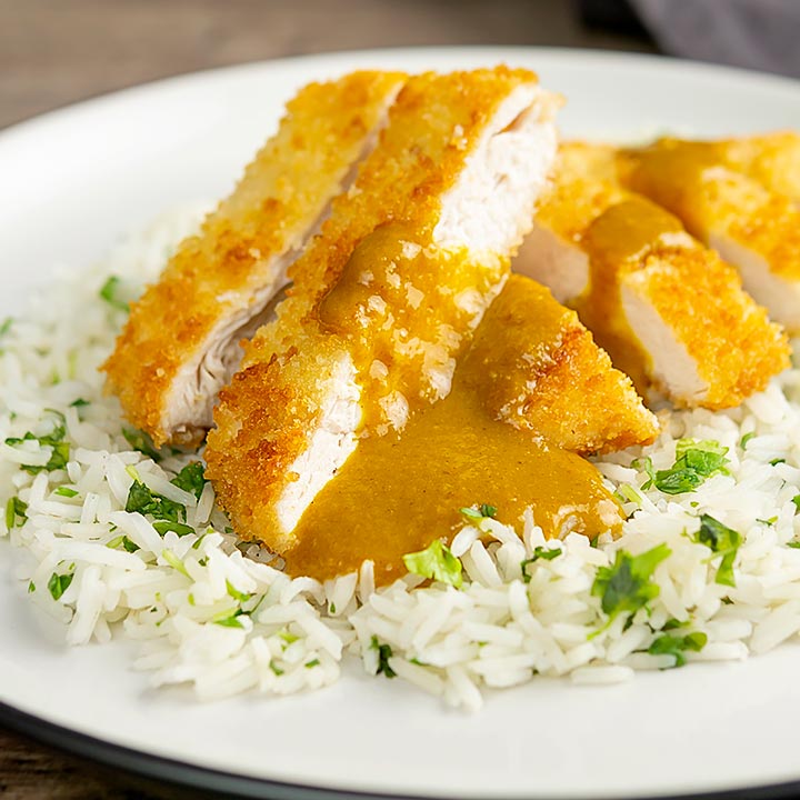 Square image of a chicken katsu curry with sliced crispy chicken breast served with coriander rice