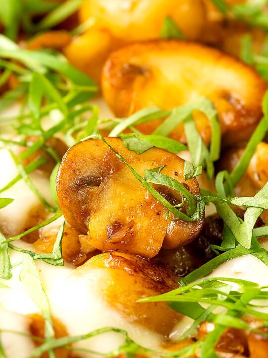 Portrait close up image of baked gnocchi with mushrooms in balsamic vinegar, mozzarella cheese and fresh basil